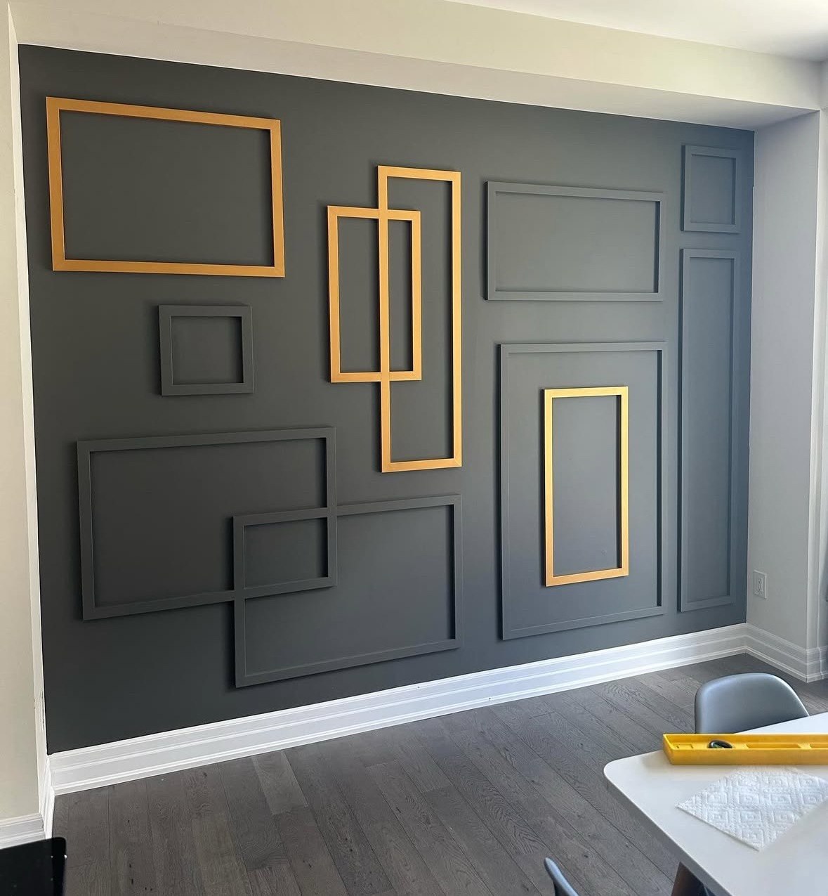 Custom geometric accent wall with dark paint and gold molding frames installed in Triangle NC home