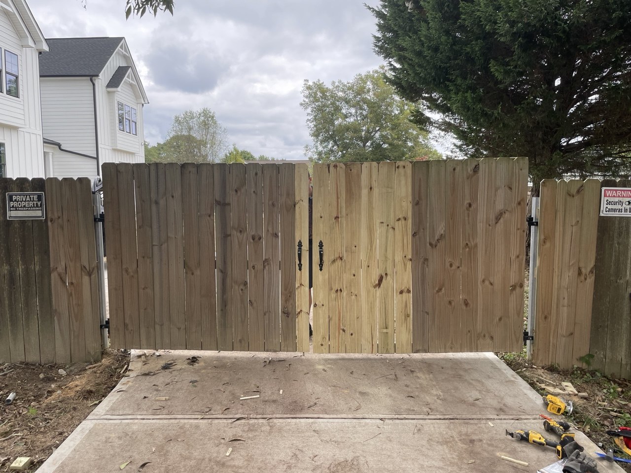 Wood fence double gate with partial plank replacement — new pressure-treated boards installed alongside existing fence in Triangle NC