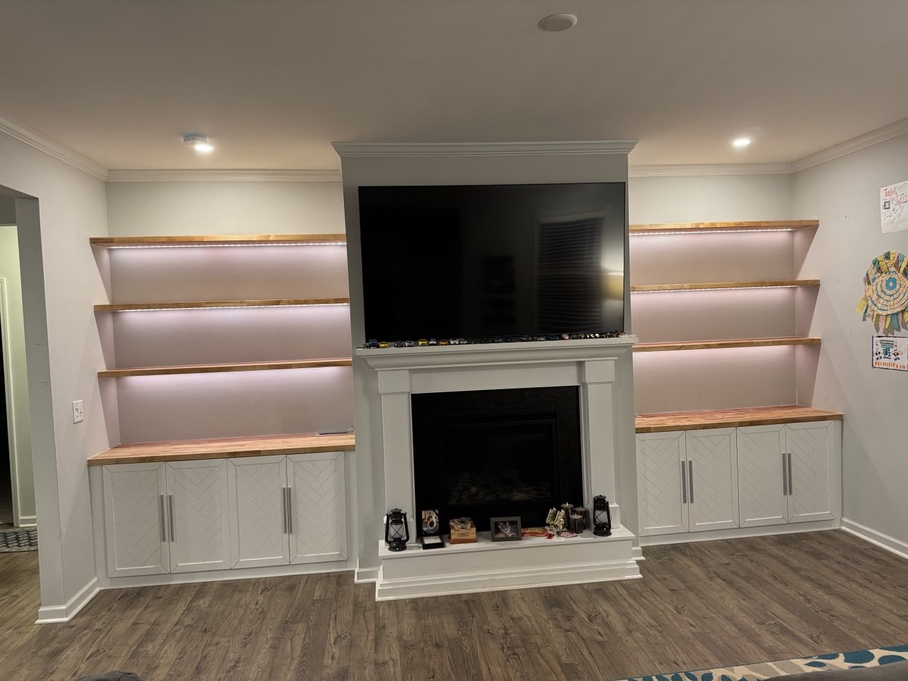 Custom built-in cabinets and wood shelves with LED lighting around fireplace in Triangle NC living room