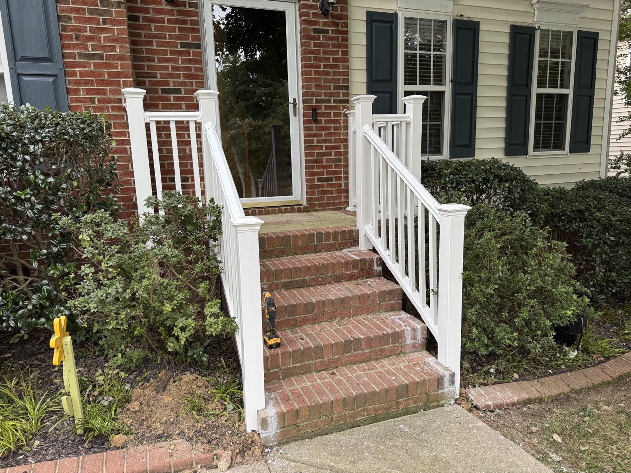 New white vinyl front porch railing with decorative posts installed on brick steps in Triangle NC home